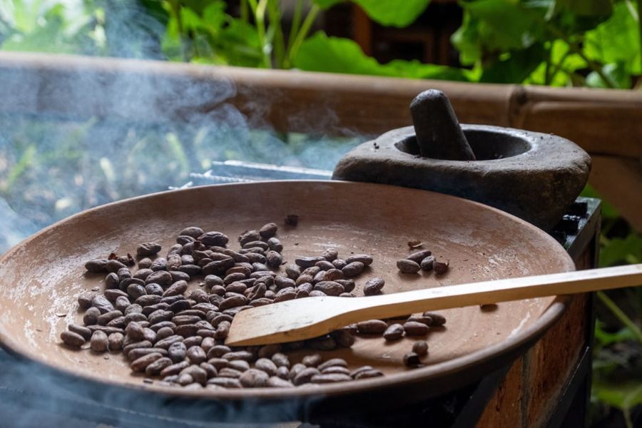 Cacao beans roasting in a clay pan on a chocolate tour in Mindo