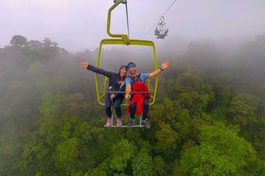 Visitors riding a cable chair above the cloud forest canopy as the morning mist lifts, Mindo