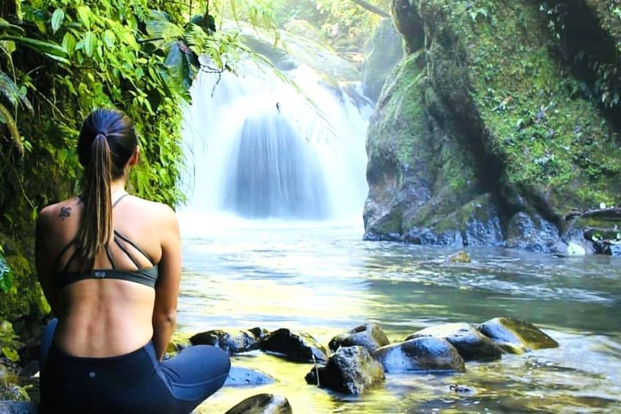 Visitor sitting beside a waterfall pool in the cloud forest near Mindo